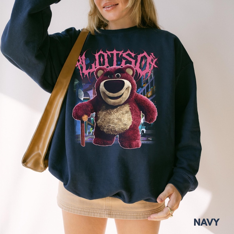 K&ouml;nnte beinhalten: Marineblaues Sweatshirt mit einem Aufdruck von Lotso, einem roten B&auml;ren, und dem Wort "LOTSO" in rosa Schrift. Der B&auml;r h&auml;lt einen kleinen Stock. Das Sweatshirt hat eine marineblaue Farbe.