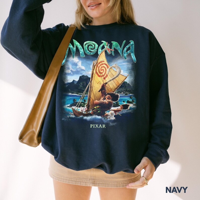 Pu&ograve; includere: Felpa blu navy con grafica del film "Moana". Il design include il titolo del film, una barca con un personaggio e la scritta "PIXAR". La felpa &egrave; a girocollo.