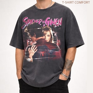 May include: Dark grey t-shirt with a graphic of Spider-Man and Gwen Stacy, and the text "Spider-Gwen" in pink and purple. The shirt has a vintage, distressed appearance, and the text "Pepper T-Shirt Comfort" is printed at the top.