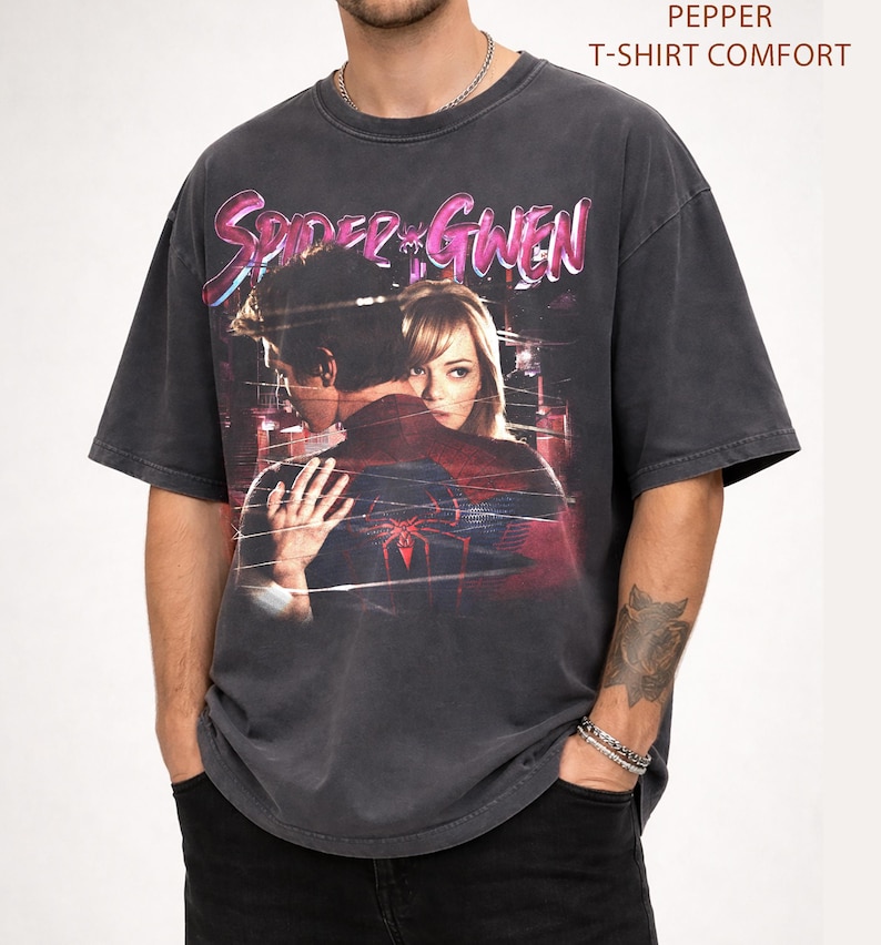May include: Dark grey t-shirt with a graphic of Spider-Man and Gwen Stacy, and the text "Spider-Gwen" in pink and purple. The shirt has a vintage, distressed appearance, and the text "Pepper T-Shirt Comfort" is printed at the top.