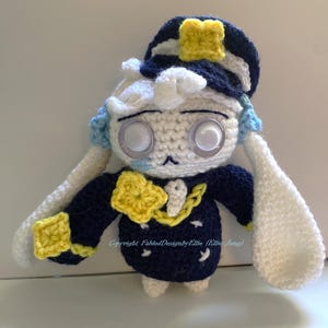 Puede incluir: Muñeca de ganchillo hecha a mano con uniforme azul marino y gorro blanco y azul marino. La muñeca tiene ojos grandes y claros, pelo blanco y brazos largos y blancos. Acentos amarillos en el sombrero, cuello y puños. Un artículo único y artesanal.