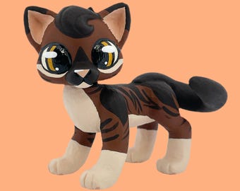 May include: A handcrafted cat figurine with a brown and black tabby pattern. The cat has large, expressive eyes with yellow accents, a white chest, and paws. The figurine is posed in a standing position, showcasing its detailed design.
