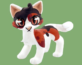 Könnte beinhalten: Handgefertigte Keramik-Katzenfigur im Calico-Muster. Die Katze hat eine weiße Basis mit schwarzen und rotbraunen Flecken. Die Augen sind groß und detailliert, mit passender rotbrauner Farbe. Die Figur ist in einer stehenden Position dargestellt.