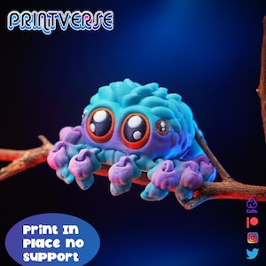 Puede incluir: Una araña de juguete impresa en 3D, con cuerpo azul y patas moradas. La araña tiene ojos grandes y expresivos y está posada en una rama. La imagen incluye el texto "Print in Place no support" y el logotipo de Printverse.