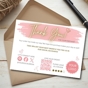 Puede incluir: Una tarjeta de agradecimiento rosa y blanca con texto dorado. La tarjeta incluye el texto "Thank You!" y "FOR YOUR PURCHASE!". También tiene iconos de redes sociales y un código QR. La tarjeta está dentro de un sobre marrón.