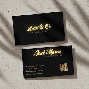 Puede incluir: Dos tarjetas de visita negras con letras doradas. La tarjeta superior dice "Artist & Co MAKEUP ARTIST". La tarjeta inferior dice "Jack Mason MAKEUP ARTIST" con información de contacto y un código QR.