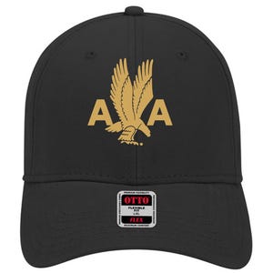 May include: Black baseball cap with a gold eagle graphic and the letters "A" on either side. The cap has a curved brim and a flexible fit. The brand label "OTTO" is visible on the front.