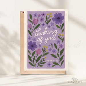 May include: A greeting card with a floral design and the words "thinking of you." The card features purple, pink, and yellow flowers with green leaves on a lavender background. The text "Isaiah 41:10" is also included.
