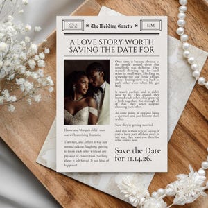 May include: A rectangular wedding save the date card designed like a newspaper titled The Wedding Gazette. It features a photograph of a couple, text detailing their love story, and the date 11.14.26 printed in black ink on off-white paper.