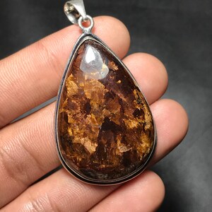 May include: A set of three ceramic mugs with a speckled, cream-colored glaze. Each mug features a different hand-painted design: a blue and green leaf, a yellow flower, and a red berry. The mugs have a simple, modern design.