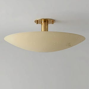 Könnte beinhalten: Eine Deckenleuchte im Mid-Century-Modern-Stil. Sie hat einen cremefarbenen, ovalen Schirm mit kleinen, gleichmäßig verteilten Perforationen. Getragen wird sie von einem messingfarbenen Stiel und einer kreisförmigen Basis.
