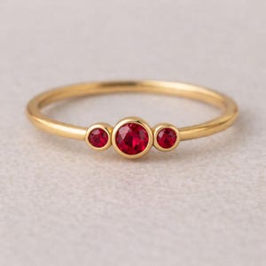 Könnte beinhalten: Eine weiße Keramik-Tasse mit schwarzem Henkel und dem Text "But First, Coffee" in fetter, schwarzer Schrift. Die Tasse steht vor einem verschwommenen Hintergrund, der eine gemütliche Umgebung suggeriert.