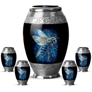 May include: A collection of black urns with silver accents. The central urn features a large, detailed bee illustration with blue and gold hues against a starry background. Smaller urns with similar bee designs surround the main piece.