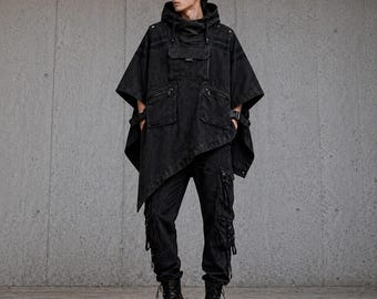 May include: Black denim hooded poncho with multiple pockets, worn with black cargo trousers and boots. The outfit has a modern, urban style. The poncho's design is asymmetrical.