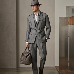 Luxury men’s grey tailored outfit shown in a minimalist indoor photoshoot with polished formal styling.