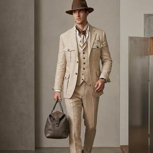 Formal beige menswear outfit with safari-inspired blazer, tailored trousers, waistcoat, scarf detail, and modern wedding style.