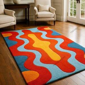 May include: A colorful area rug with a wavy design in shades of red, orange, yellow, and blue. The rug is rectangular and placed on a hardwood floor, adding a vibrant touch to the room's decor.