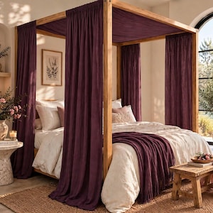 May include: A four-poster wooden bed frame draped with deep purple curtains and a matching purple throw blanket. The bed is dressed in cream-colored bedding with several pillows, positioned within a room featuring natural light and wooden accents.
