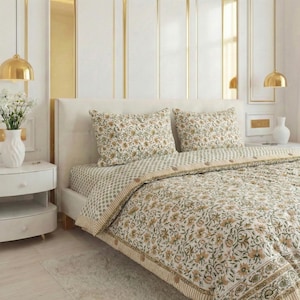 May include: A bed with a floral patterned duvet cover and two matching pillowcases. The bedding features a cream background with a repeating pattern of yellow and green flowers. The bed is made up with a fitted sheet with a dotted pattern.