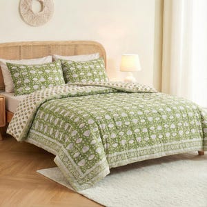 Può includere: Un set di trapunte a fantasia floreale verde e bianca su un letto. Il set comprende una trapunta e due federe. Il letto ha una testiera in rattan e un tappeto bianco. Una lampada è sul comodino.