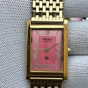 Reloj Seiko de cuarzo vintage / Esfera rosa / Brazalete dorado / Caja rectangular en tono dorado