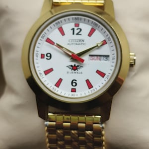 Reloj Citizen automático para hombre, esfera blanca, detalles rojos, 21 joyas, día y fecha, brazalete de oro.