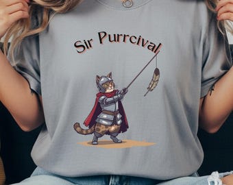 May include: Gray t-shirt featuring a cartoon cat in knight's armor holding a feather on a stick. The text "Sir Purrcival" is arched above the cat illustration. The cat is wearing a red cape and silver armor.