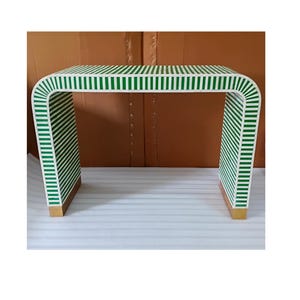 May include: A white and green striped console table with a curved design. The table has a rectangular top and two legs. The legs and top are covered in vertical green and white stripes. The table is approximately 30 inches long.