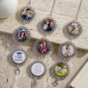 May include: A collection of silver-toned photo pendants with various images, including graduation photos and a dog. Each pendant has a decorative filigree frame and hangs from a delicate chain. Some pendants have charms like a horseshoe or an angel wing.