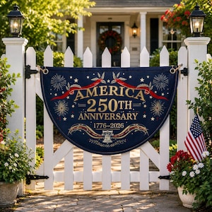Puede incluir: Una pancarta azul marino con letras y detalles dorados, que celebra el 250 aniversario de América de 1776-2026. La pancarta está colgada en una valla blanca, con una bandera americana y flores cerca.