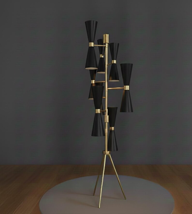 May include: A tall, mid-century modern floor lamp with a brass finish and black cone-shaped shades. The lamp has a tripod base and multiple light sources, creating a stylish and functional lighting fixture. The design is sleek and elegant.