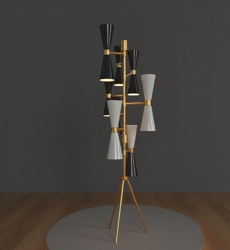 May include: A modern floor lamp with a gold-colored tripod base and a vertical structure. The lamp features multiple black and white cone-shaped shades, arranged in a tiered design. The lamp is a stylish lighting fixture.