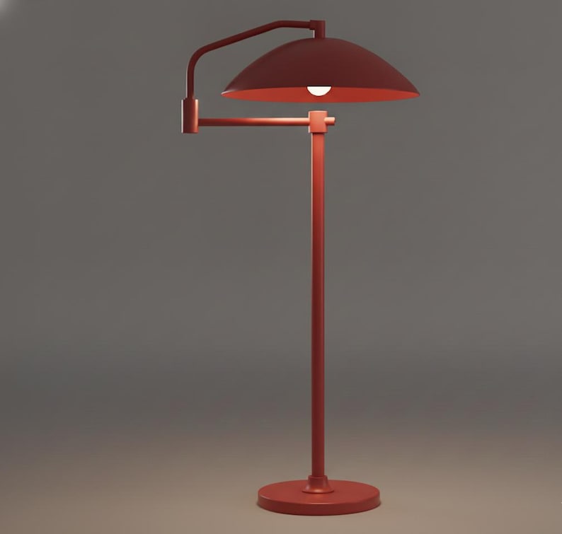 May include: A red floor lamp with a curved arm and a dome-shaped shade. The lamp has a round base and a straight pole. The light bulb is visible inside the shade. The lamp is made of metal.