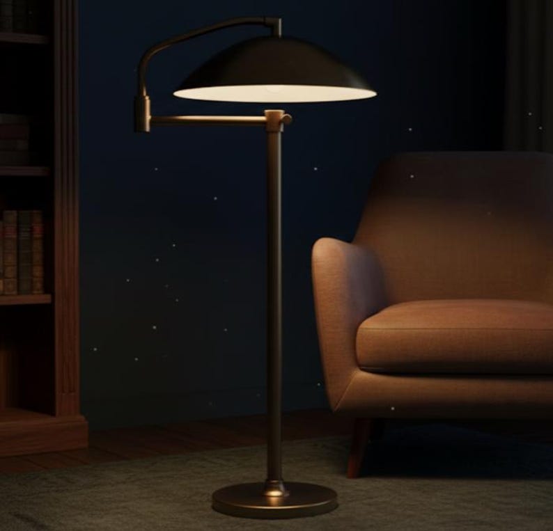 May include: A black floor lamp with a curved arm and a wide, dome-shaped shade. The lamp has a brass-coloured base and a warm, inviting glow. The lamp is next to a brown armchair.