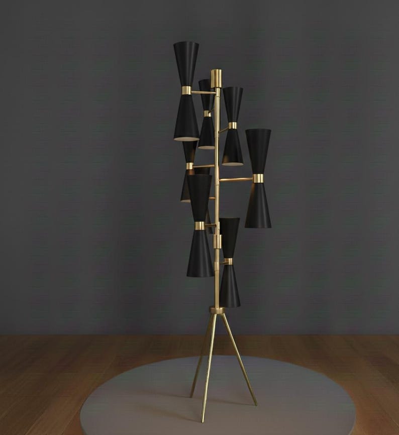 May include: A tall, modern floor lamp with a gold-colored frame and multiple black cone-shaped shades. The lamp has a tripod base and is designed with a mid-century modern aesthetic. The shades are arranged in a tiered fashion.