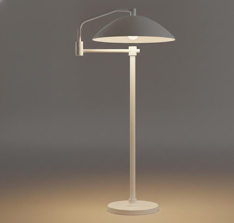 May include: A white floor lamp with a curved arm and a dome-shaped lampshade. The lamp has a circular base and a straight pole. The lampshade is angled downwards, and the light bulb is visible.