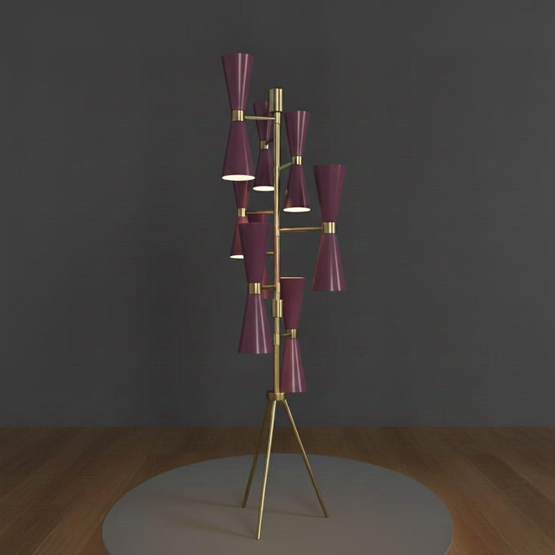 May include: A modern floor lamp with a brass tripod base and a vertical structure supporting multiple burgundy-colored cone-shaped shades. The lamp has a mid-century modern design, with a warm, inviting glow.