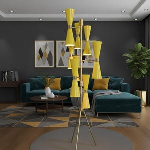 May include: A tall, modern floor lamp with a brass finish and multiple yellow cone-shaped shades. The lamp stands on a tripod base and illuminates a living room with a teal sofa, geometric rug, and artwork. The lamp's height is approximately 72 inches.