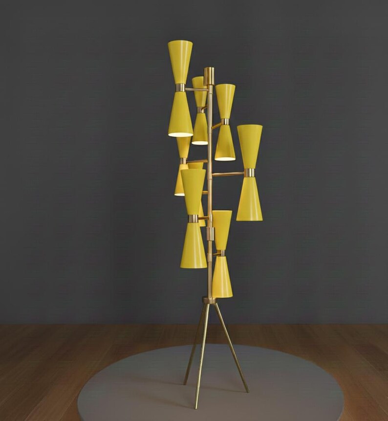 May include: A tall, mid-century modern floor lamp with a brass frame and multiple yellow cone-shaped shades. The lamp has a tripod base and a series of horizontal bars supporting the shades. The shades are arranged in a vertical, staggered pattern.