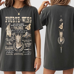 May include: A charcoal gray short-sleeve t-shirt featuring a graphic print. The front displays the text "FOURTH WING" and "VIOLENCE" with dragon illustrations, clouds, a sword, and various quotes. The back features a vertical design of a dragon.