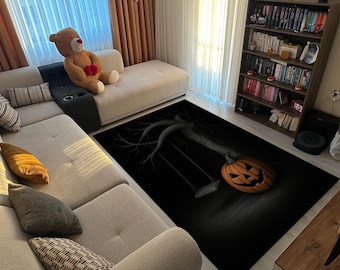 May include: Black rectangular rug featuring a Halloween-themed design. The rug depicts a carved orange pumpkin with a smiling face, a tree branch, and a swing set against a dark background. The rug is placed in a living room setting.