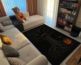 May include: Black rectangular Halloween-themed rug featuring a spooky tree design with glowing orange eyes and a jack-o'-lantern. A swing hangs from a branch. The rug is placed in a living room with a beige sectional sofa and a teddy bear.