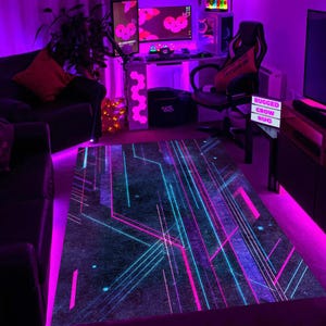 May include: A rectangular rug with a dark background and a neon geometric design in shades of pink and blue. The rug features straight and angled lines, creating a modern, tech-inspired pattern. The rug is placed in a room with purple ambient lighting.