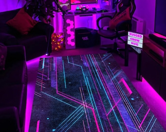May include: A rectangular rug with a dark background and a neon geometric design in shades of pink and blue. The rug features straight and angled lines, creating a modern, tech-inspired pattern. The rug is placed in a room with purple ambient lighting.