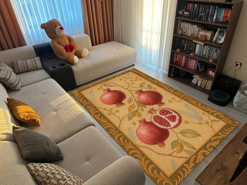K&ouml;nnte beinhalten: Rechteckiger Teppich mit beigem Hintergrund und Granatapfel-Fruchtmuster. Der Teppich hat einen dekorativen Rand und befindet sich in einem Wohnzimmer mit Sofa und B&uuml;cherregal. Die Ma&szlig;e des Teppichs sind in Zentimetern.