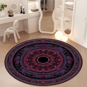 May include: A round rug with a detailed mandala design in shades of black, purple, and red. The rug features an intricate floral pattern and a central dark circle, suitable for a living room or bedroom.