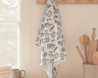 May include: A white kitchen towel with a black science-themed pattern, including illustrations of cells, DNA, and a microscope, hangs from a wooden rack. The towel is folded and draped, showcasing the repeating design.