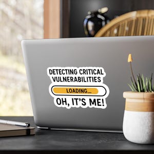 Op de afbeelding: Een witte sticker op een laptop met de tekst "DETECTING CRITICAL VULNERABILITIES" boven een laadbalk en de woorden "OH, IT'S ME!". De sticker heeft een zwarte rand.