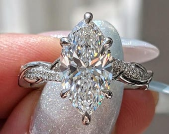 Peut inclure: Une bague argentée avec une grande pierre centrale taille marquise fixée par six griffes. L'anneau présente un design torsadé avec de petites pierres serties pavé incrustées le long du métal, créant un aspect scintillant sur la tige.