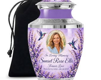 Puede incluir: Una urna funeraria morada con un retrato ovalado central, rodeada de flores de lavanda y dos colibríes. El texto dice In Loving Memory, Sunset Rose Ellis, Forever Love, Born 05/12/1970 - 09/28/2025. Incluye una bolsa negra.